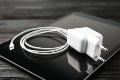 Tablet and charging cable with adapter on table, closeup