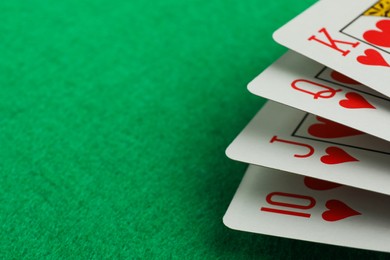 Photo of Hand of playing cards on green table, closeup. Space for text