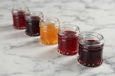Jars of different jams on white marble table