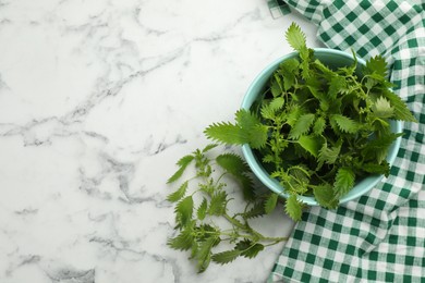 Fresh stinging nettle leaves on white marble table, flat lay. Space for text