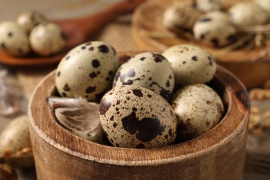 Wooden bowl with quail eggs on table, closeup