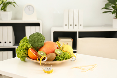 Nutritionist's workplace with fruits, vegetables, measuring tape and body fat caliper on table