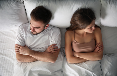 Unhappy couple with relationship problems after quarrel in bed, above view