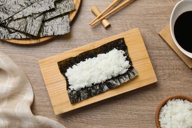 Dry nori sheet with rice on wooden table, flat lay
