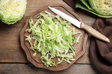 Photo of Cut fresh savoy cabbage on wooden table, flat lay
