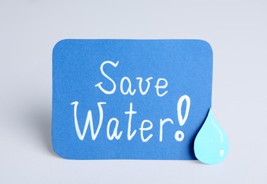 Photo of Card with words Save Water and paper drop on light grey background