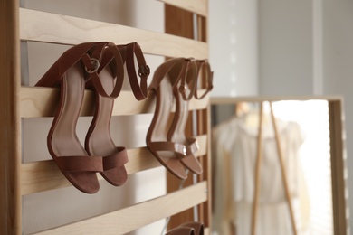 Rack with stylish women's high heeled shoes in dressing room. Modern interior design
