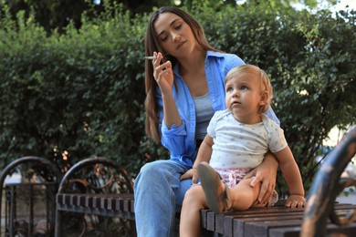 Photo of Mother with cigarette and child outdoors. Don't smoke near kids