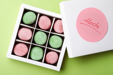 Many different delicious mochi in box on green background, top view. Traditional Japanese dessert