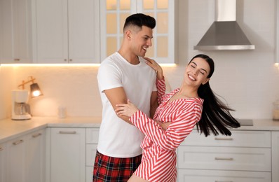 Photo of Happy couple wearing pyjamas and dancing in kitchen