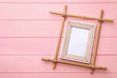 Empty bamboo frame on pink wooden background, top view. Space for text