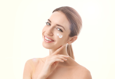 Young woman with sun protection cream on face against white background