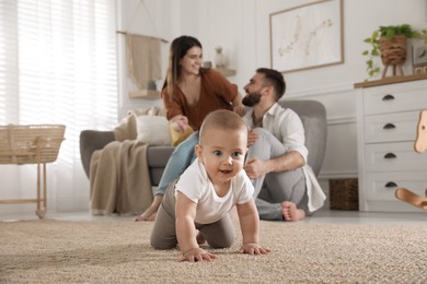 Happy parents watching their baby crawl on floor at home