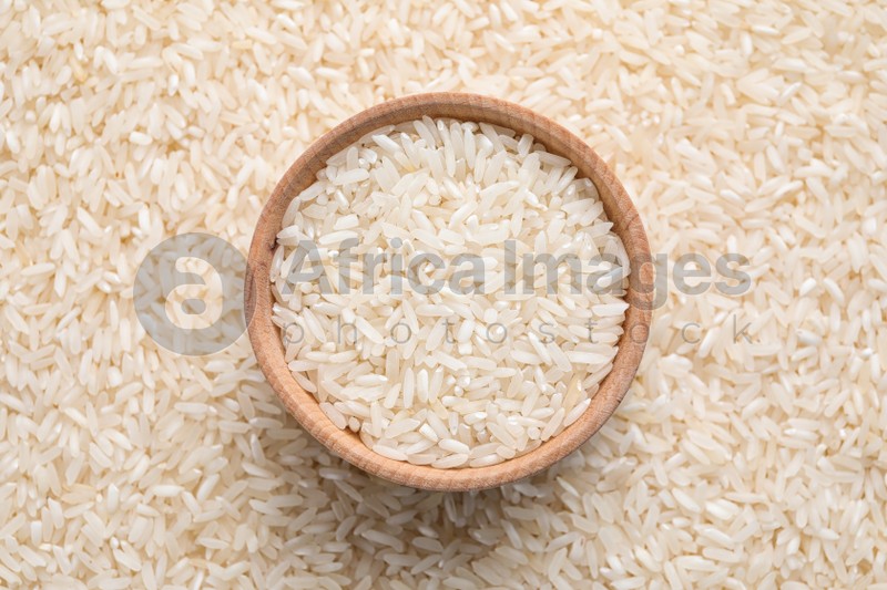 Pile of polished rice and wooden bowl, top view