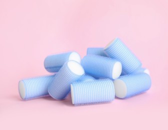 Many light blue hair curlers on pink background