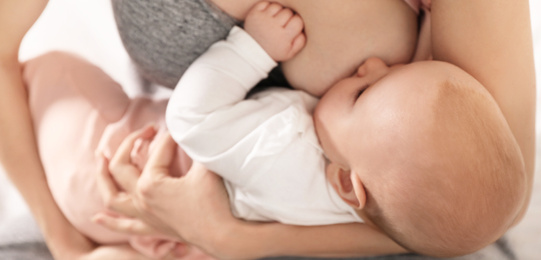 Young woman breast feeding her little baby, closeup. Banner design