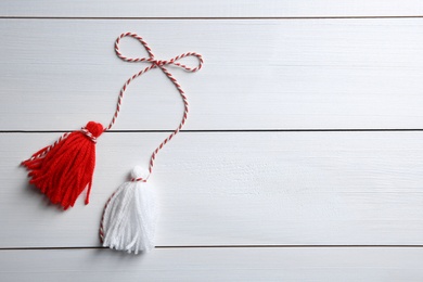 Photo of Traditional martisor on white wooden background, top view with space for text. Beginning of spring celebration