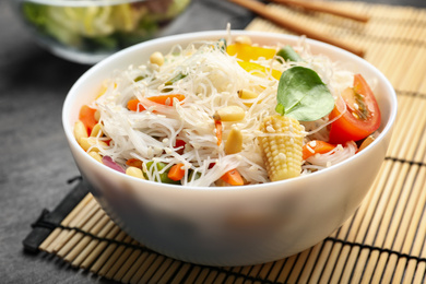 Tasty cooked rice noodles with vegetables on grey table