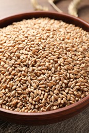 Photo of Bowl full of wheat grains on table, closeup