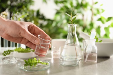 Scientist making cosmetic product at grey table, closeup
