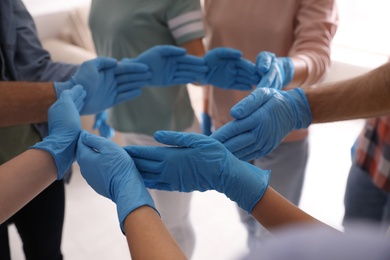 People in blue medical gloves showing circle with hands on light background, closeup