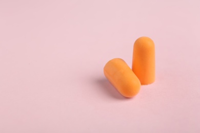 Pair of orange ear plugs on pink background. Space for text