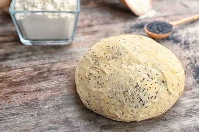 Raw dough with poppy seeds on wooden table
