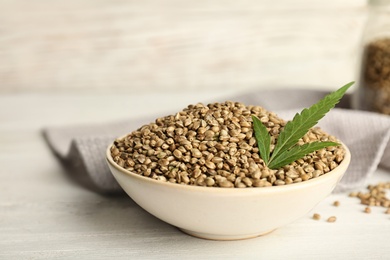 Bowl of hemp seeds on table against wooden wall