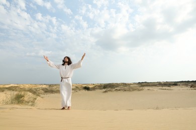 Jesus Christ raising hands in desert. Space for text