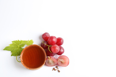 Organic red grapes, seeds and bowl of natural essential oil on white background, flat lay. Space for text