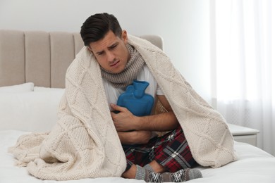 Ill man with hot water bottle suffering from cold at home