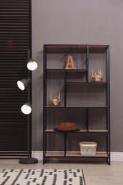 Stylish shelving unit with decor and lamp near grey wall indoors. Interior design