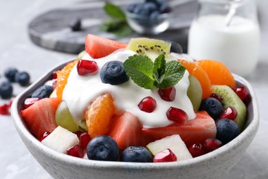 Delicious fruit salad with yogurt in bowl on table, closeup