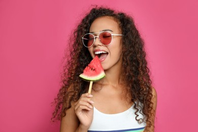 Beautiful young African American woman eating watermelon on crimson background