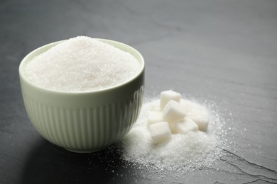 Photo of Granulated sugar in bowl on dark table