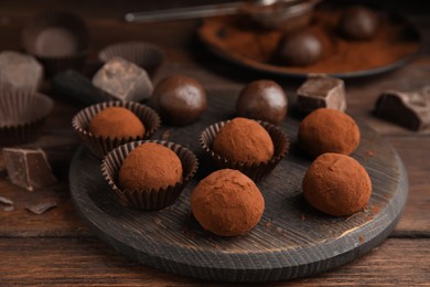 Delicious chocolate truffles powdered with cocoa on wooden table