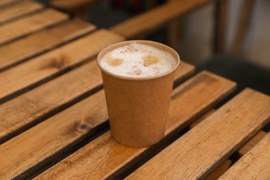Takeaway paper cup with coffee on wooden table