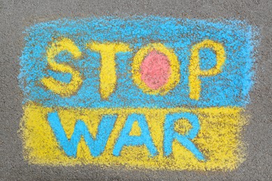Ukrainian flag with words Stop War drawn with colorful chalks on asphalt outdoors, top view