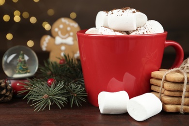 Delicious cocoa drink with marshmallows and Christmas decor on wooden table, closeup