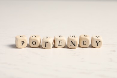 Wooden cubes with word Potency on white table, closeup