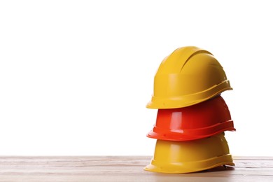 Different hard hats on wooden table against white background. Space for text