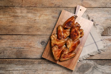 Photo of Board with delicious fried chicken wings on wooden table, top view. Space for text