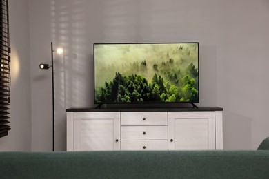 Modern TV on cabinet near white wall in living room