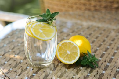 Photo of Refreshing water with lemon and mint on glass table