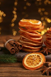 Photo of Dry orange slices, anise stars and cinnamon sticks on wooden table. Bokeh effect