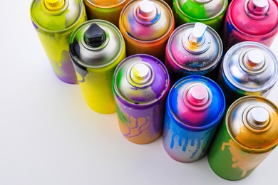 Used cans of spray paints on white background, above view. Graffiti supplies