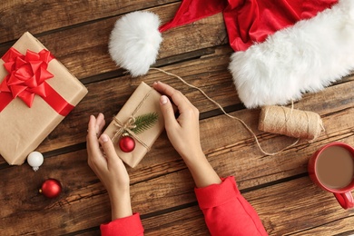 Woman with Christmas gift boxes at wooden table, top view