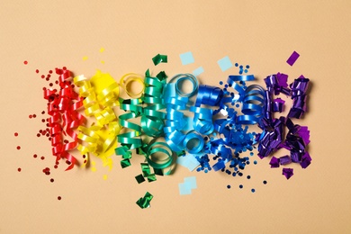 Colorful serpentine streamers and confetti on beige background, flat lay