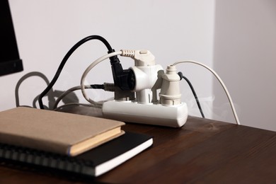 Photo of Smoking plug in power strip on wooden table. Electrical short circuit
