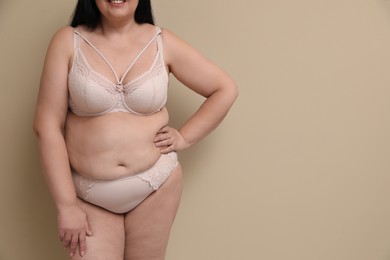 Beautiful overweight woman in underwear on beige background, closeup with space for text. Plus-size model
